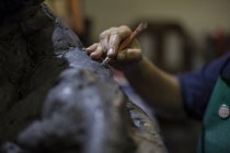 Cropped view of sculptor in artist studio creating sculpture with hand tool — Stock Photo