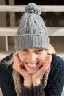 Portrait d'une jeune femme souriante portant un chapeau tricoté — Photo de stock