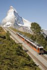 Zug auf Bergbahn nahe schneebedecktem Gipfel — Stockfoto