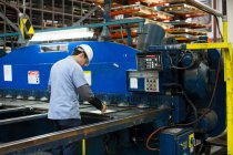 Travailleur utilisant des machines dans une usine métallique — Photo de stock