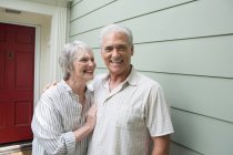 Senior couple smiling together outside house, portrait — Stock Photo