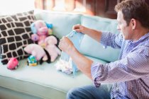 Mann faltet Babykleidung auf Sofa — Stockfoto