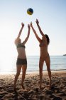 Frauen spielen mit Volleyball am Strand — Stockfoto