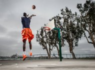 Молодий баскетболіст стрибає, щоб забити — стокове фото