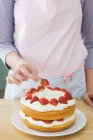 Abgeschnittenes Bild einer Frau, die Kuchen mit Erdbeeren zubereitet — Stockfoto