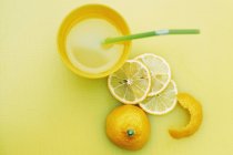 Стакан лимонного сока и нарезанный лимон на столе — стоковое фото