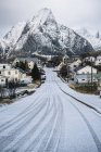 Snow covered road and rock, Reine, Lofoten, Noruega - foto de stock