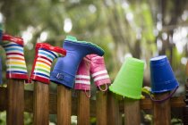 Rubber boots and buckets on top of garden fence — Stock Photo