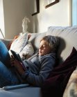 Adolescente relajándose en el sofá y utilizando la tableta digital - foto de stock