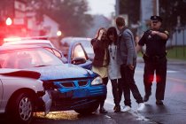 Young people and police officer at scene of car crash — Stock Photo