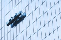 Low angle view of Suspended window cleaning platform on glass building — Stock Photo