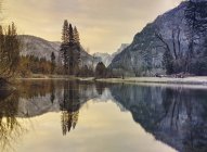 Montañas y árboles reflejándose en el agua del lago - foto de stock