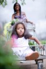 Menina sentada no carrinho no berçário da planta — Fotografia de Stock