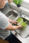 Homme lavant la salade dans la cuisine — Photo de stock