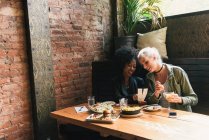 Amigos compartiendo comida juntos en la cafetería - foto de stock