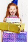 Screaming girl with stack of birthday gifts — Stock Photo