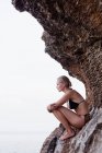 Femme assise sur les rochers aux falaises — Photo de stock
