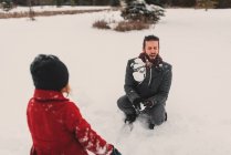 Девушка бросает снежок в своего отца — стоковое фото