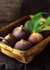 Figos frescos e folha na cesta tecida — Fotografia de Stock
