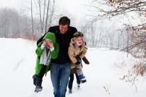 Père portant fils et fille dans la neige — Photo de stock