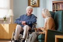 Coppia di anziani in casa di cura, uomo in sedia a rotelle — Foto stock