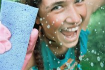 Menina de limpeza de vidro com esponja — Fotografia de Stock