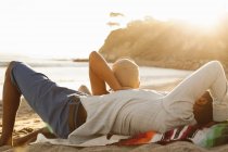 Jeune couple couché ensemble sur la plage, vue arrière — Photo de stock