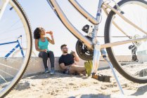 Couple relaxing after bike ride, bicycles beside them — Stock Photo