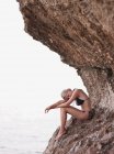 Femme assise sur des rochers aux falaises — Photo de stock