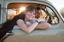 Mujeres jóvenes viajando en coche en viaje por carretera, retrato - foto de stock