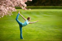 Woman in standing bow yoga position in park — Stock Photo