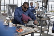 Cape Town, South Africa, machinist in workshop sanding down wood with safety goggles — Stock Photo