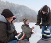 Donne e bambini costruzione pupazzo di neve — Foto stock