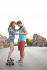 Young woman on skateboard with boyfriend — Stock Photo
