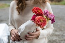 Mid section of woman holding bunch of flowers at organic farm shop — Stock Photo
