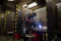 Female metalsmith welding metal at workbench — Stock Photo