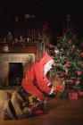 Санта Клаус розміщує подарунки під ялинкою — стокове фото