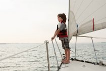 Мальчик на борту яхты, смотрит на вид — стоковое фото