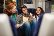 Drei junge Freunde, die im Zug unterwegs sind und Musik hören — Stockfoto