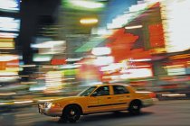Carro de táxi amarelo e luzes da cidade em borrão movimento — Fotografia de Stock