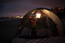Menino na tenda com colo à noite, Huntington Beach, Califórnia, EUA — Fotografia de Stock