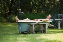 Man lying in outdoor bathtub — Stock Photo