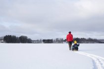 Father pulling sons along on sledge in snow covered landscape, rear view — Stock Photo
