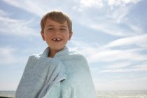 Junge am Meer, in ein Handtuch gewickelt — Stockfoto