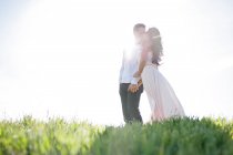 Romántica pareja besando en una colina soleada y soleada. - foto de stock