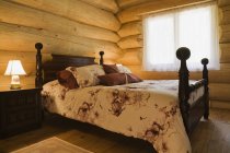 Vue en angle du lit en bois antique dans une cabane en bois blanc oriental — Photo de stock