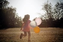Chica corriendo con globos - foto de stock