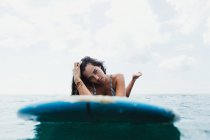 Vista de nivel de superficie de la mujer en la tabla de surf mirando a la cámara, Oahu, Hawaii, EE.UU. - foto de stock