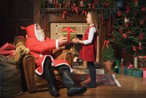 Père Noël donnant fille un cadeau — Photo de stock