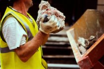 Bauarbeiter hält Schutt in der Hand — Stockfoto